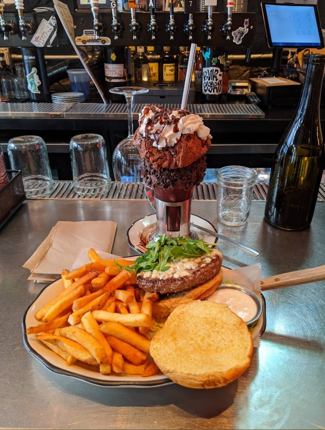 A delicious burger with a side of fries and a large chocolate milkshake topped with whipped cream, served at Black Tap Craft Burgers & Beer in SoHo, NYC